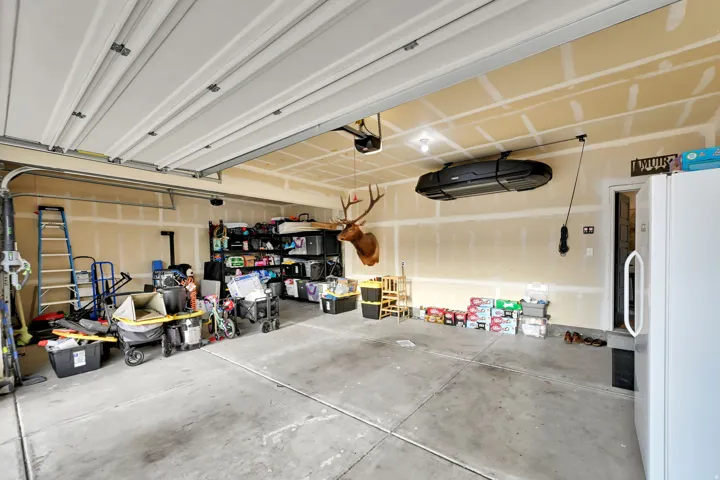 Attached garage with a concrete floor, exposed ceiling joists, and a garage door