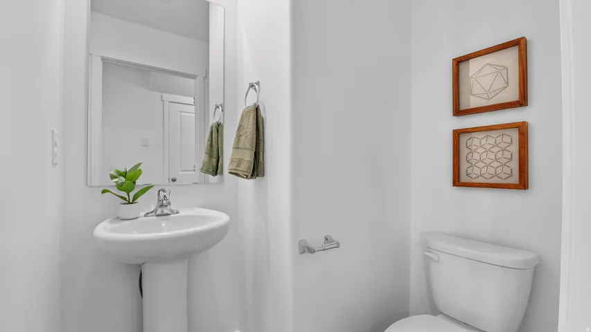 Pedestal sink with chrome faucet, rectangular wall mirror, and white toilet