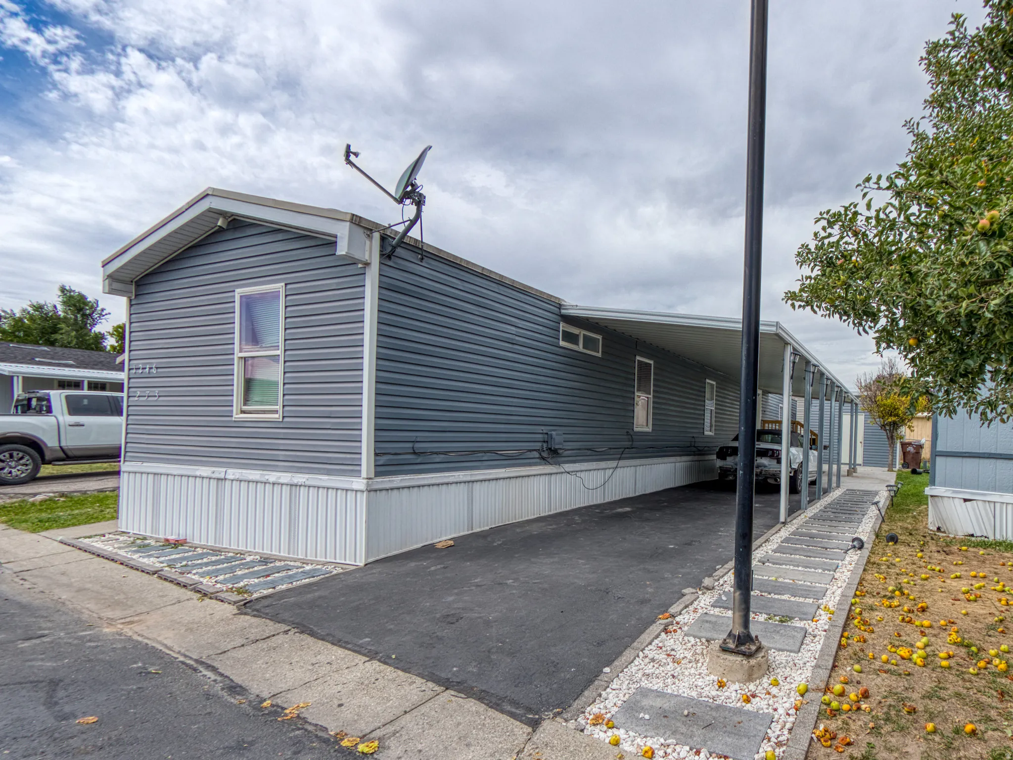 Parking exterior view with a covered carport, paved driveway, and decorative stone landscaping