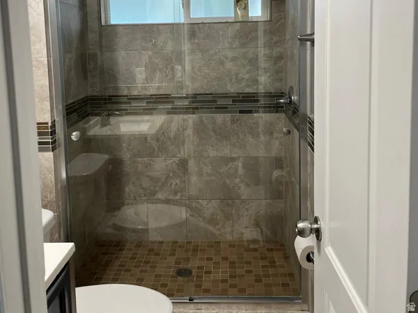 Glass-enclosed shower with large format wall tiles, mosaic tile accent band, and a mosaic tile shower pan