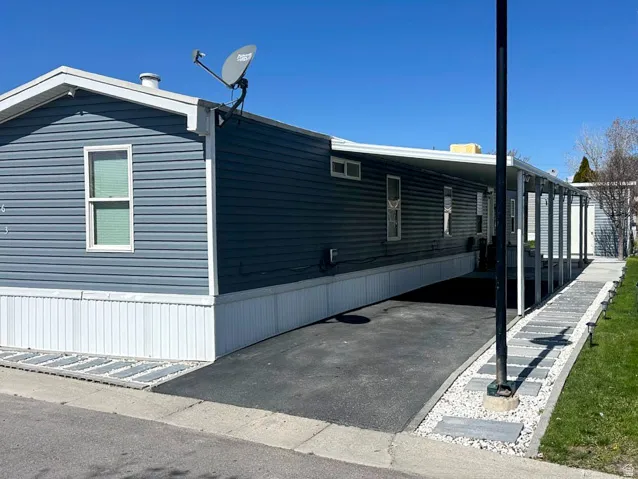 Blue siding exterior with white trim, covered carport, and a paved driveway