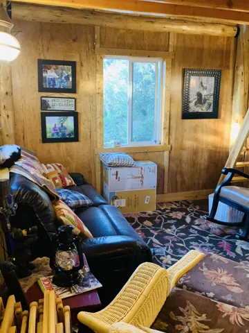 Wood-paneled walls with exposed wood beams, a double-hung window, and a ceiling-mounted light fixture