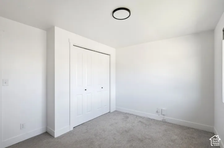 White interior walls with neutral carpet flooring, featuring a built-in closet with bi-fold doors and a ceiling-mounted light fixture