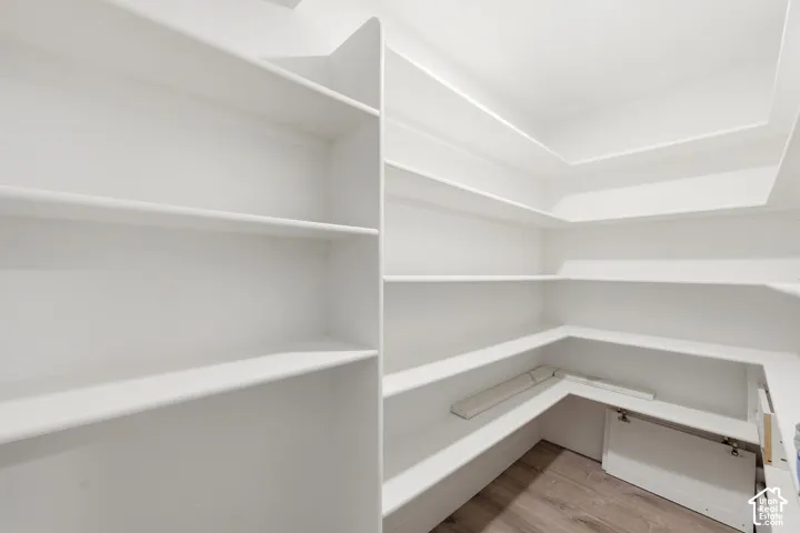 Built-in shelving with multiple storage levels, L-shaped lower shelving, and wood-finish flooring