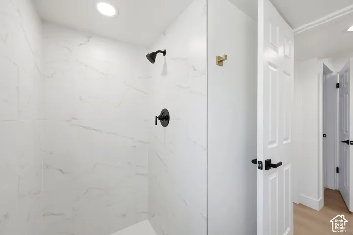 Shower featuring white veined tile, matte black fixtures, and recessed lighting