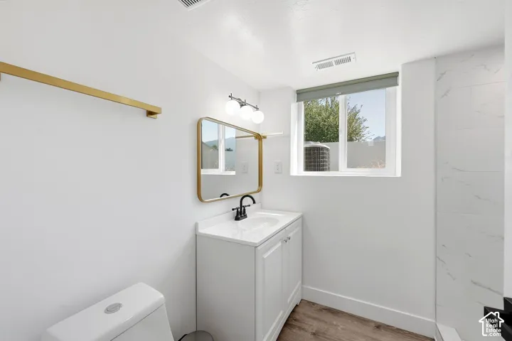 White vanity with a single basin, black faucet, and an illuminated mirror