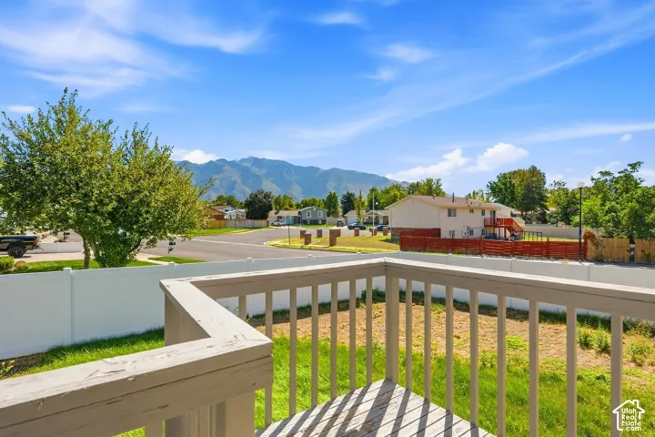Balcony with wood railing, offering a distant mountain backdrop and a white privacy fence