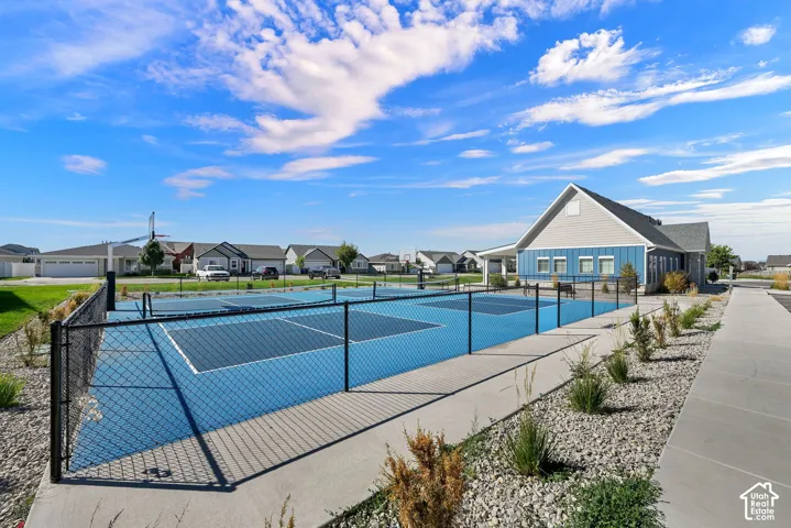 Community clubhouse with multiple outdoor courts, surrounding rock landscaping, and paved pathways