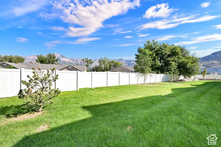 Expansive lawn area with a white privacy fence and established trees