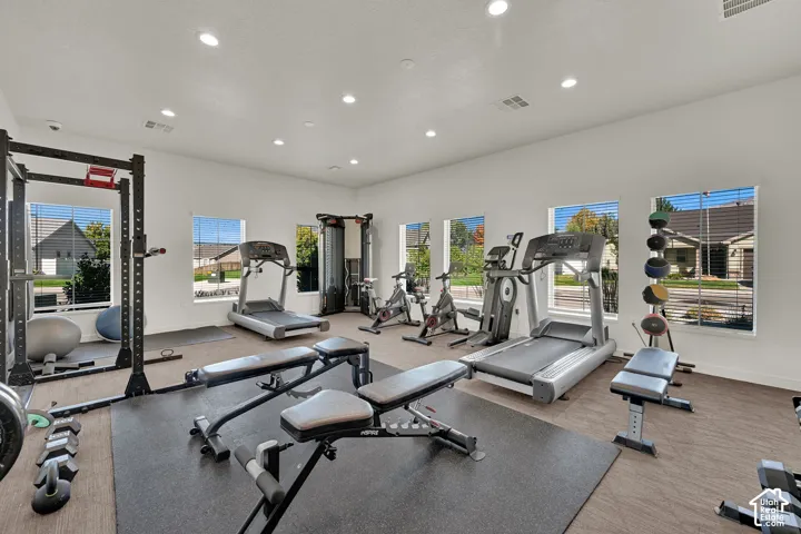 Dedicated fitness room featuring recessed lighting, multiple windows for natural light, diverse gym equipment and  rubber mats.