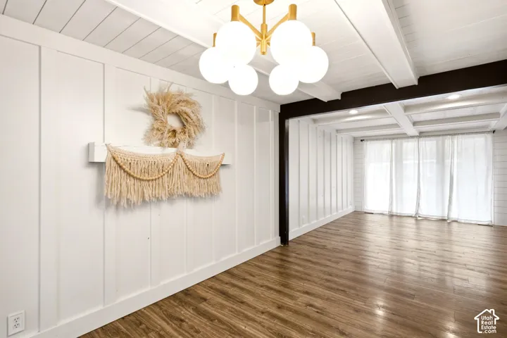 Interior space featuring board and batten wall paneling, wood-finish flooring, a coffered ceiling with recessed lighting, and a multi-globe pendant light fixture