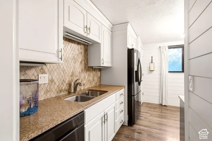 Kitchen featuring white shaker-style cabinetry, stone-finish countertops, diamond-patterned tile backsplash, stainless steel dual-basin sink, and wood-finish flooring