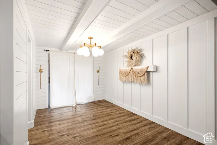 Board-and-batten wall detailing, horizontal shiplap walls, wood-finish flooring, exposed ceiling beams, and a modern multi-bulb brass chandelier