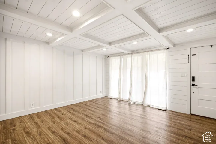Coffered ceiling with recessed lighting, board-and-batten wall detailing, horizontal plank siding, and wood-finish flooring