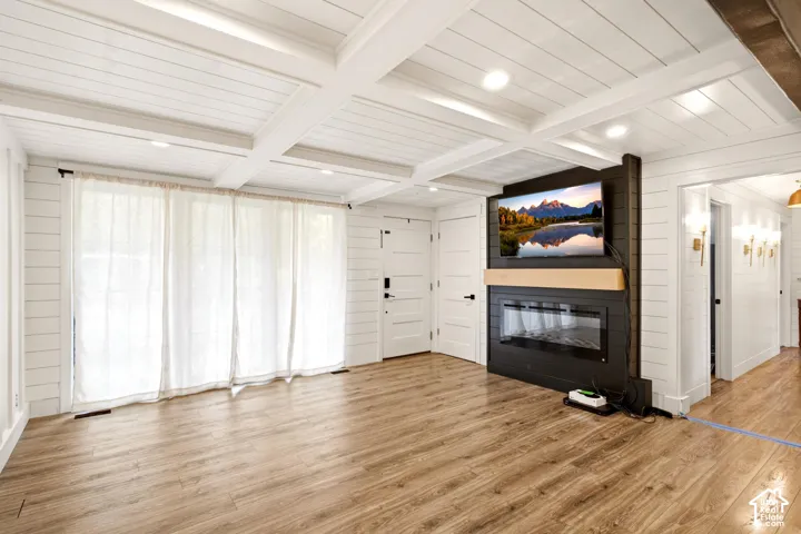 Coffered ceiling with white shiplap paneling, wood-finish flooring, recessed lighting, and a focal wall featuring a black built-in surround with a linear fireplace and natural wood mantel