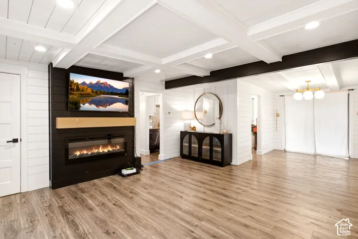 Coffered ceiling with recessed lighting, shiplap wall accents, horizontal wood-finish flooring, and a linear electric fireplace with a natural wood mantel