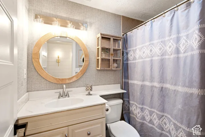 Bathroom featuring a vanity with a white countertop and oval under-mount sink, round wooden-frame mirror, wall-mounted cabinet, and horizontal light fixture