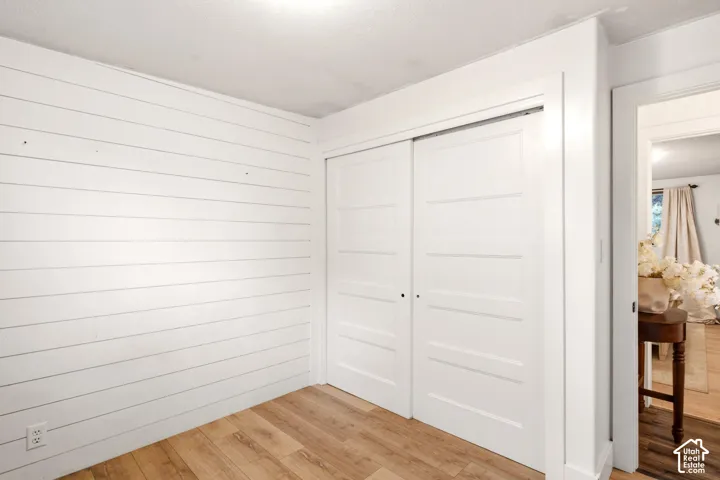 Horizontal shiplap accent wall, wood-finish flooring, and white five-panel sliding closet doors