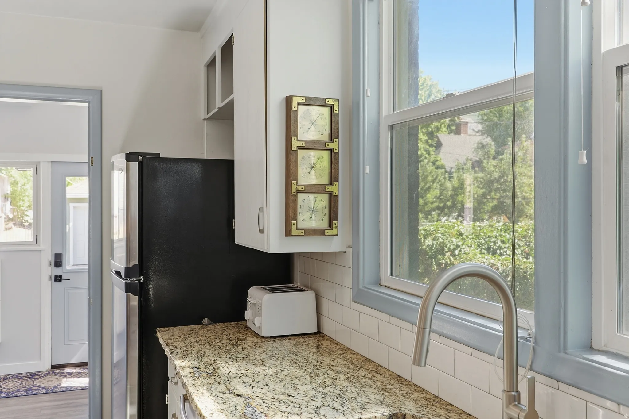 Kitchen featuring granite-style countertops, white subway tile backsplash, white cabinetry, and an undermount sink with a gooseneck faucet