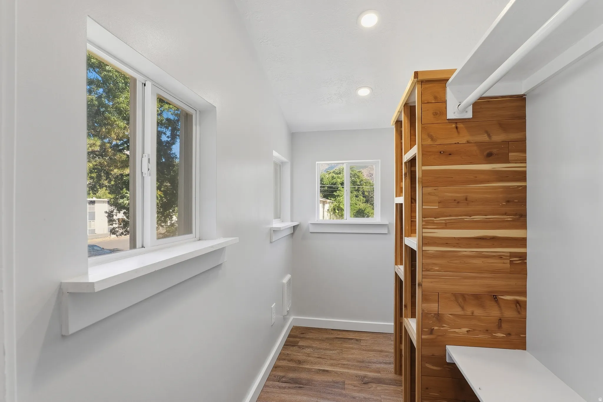 Wood-finish flooring, recessed lighting, and white walls