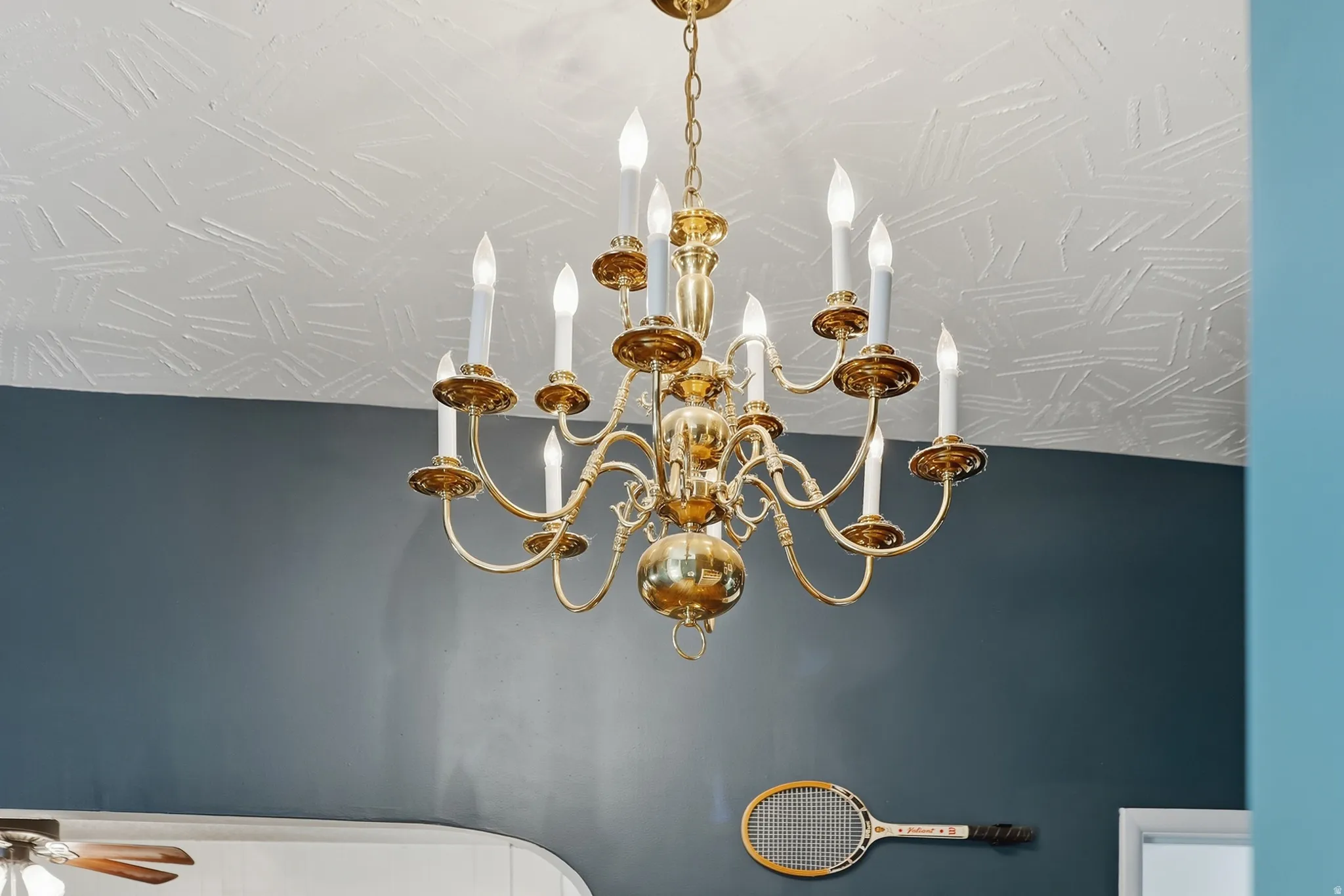 Brass chandelier with multiple candelabra bulbs and a textured ceiling
