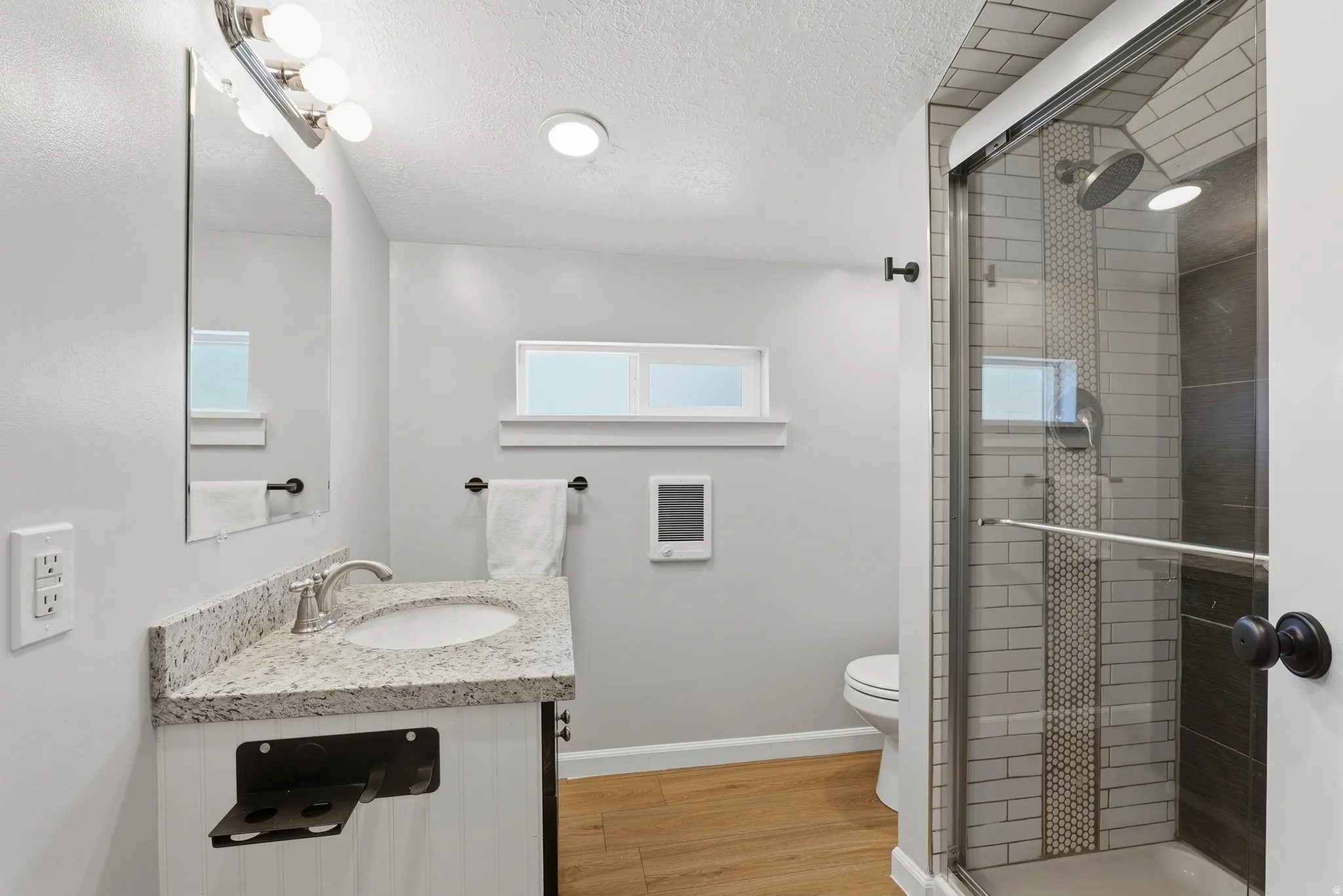 Walk-in shower with clear glass enclosure and tile surround
