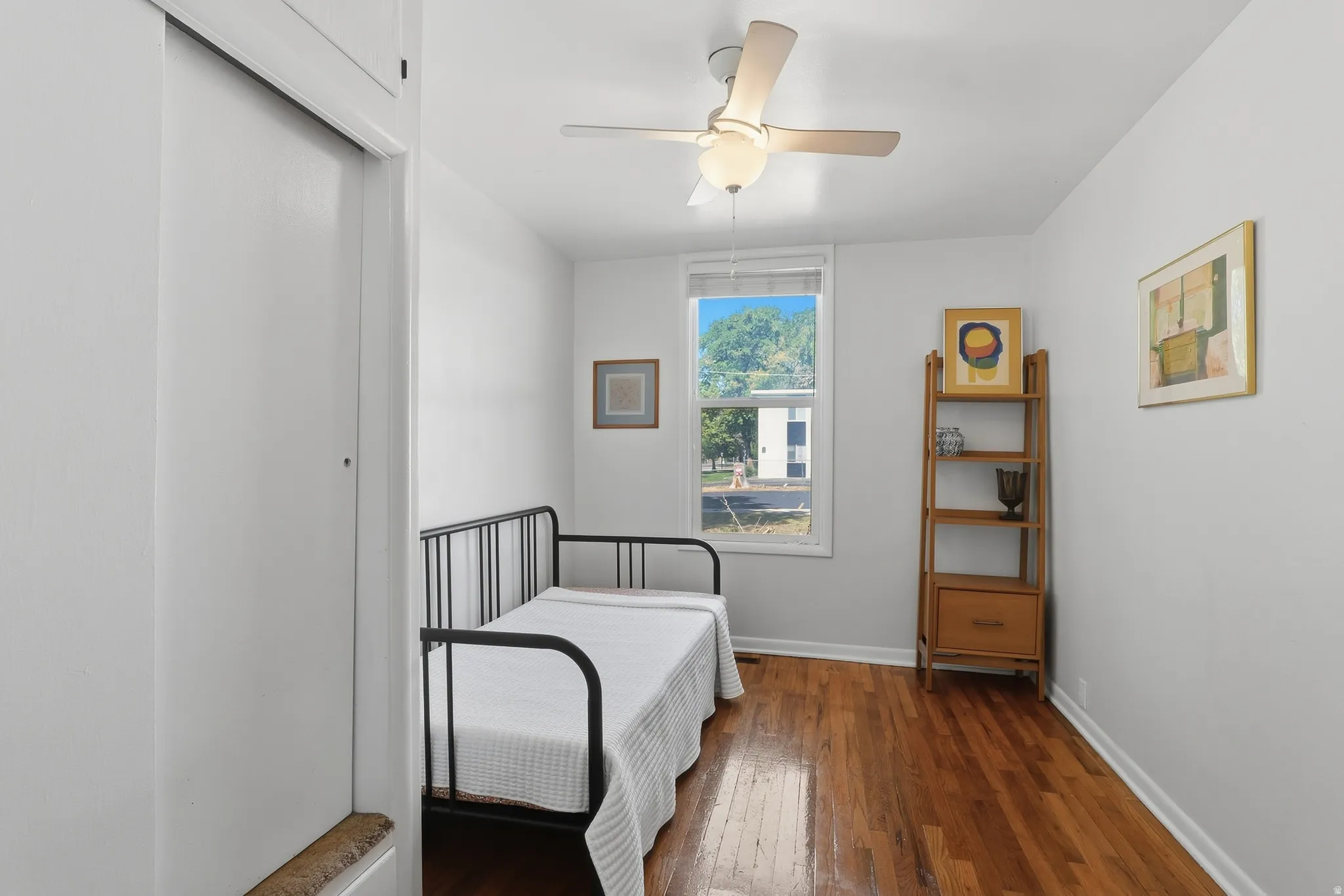 Hardwood flooring, white walls, and a ceiling fan with integrated lighting