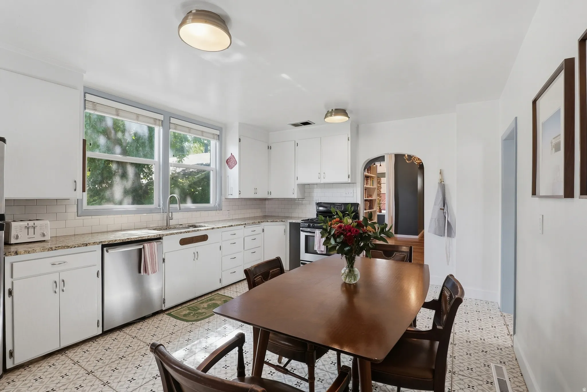 Kitchen featuring white cabinetry, light-toned countertops, subway tile backsplash, and patterned floor tiling