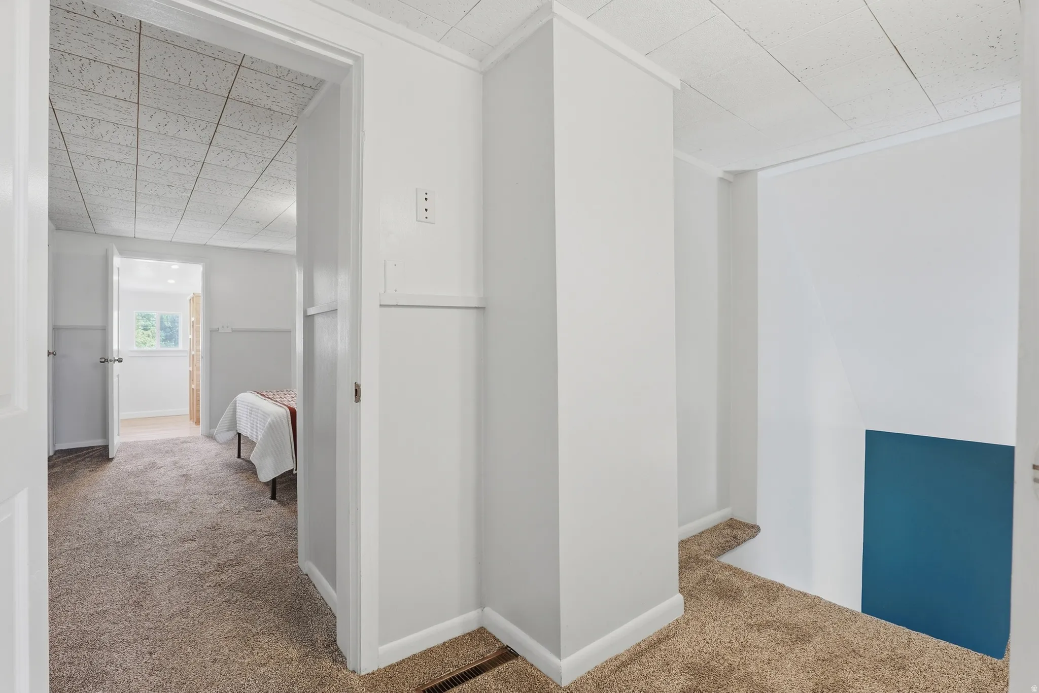 Carpeted flooring, white trim, and white walls with a board and batten detail