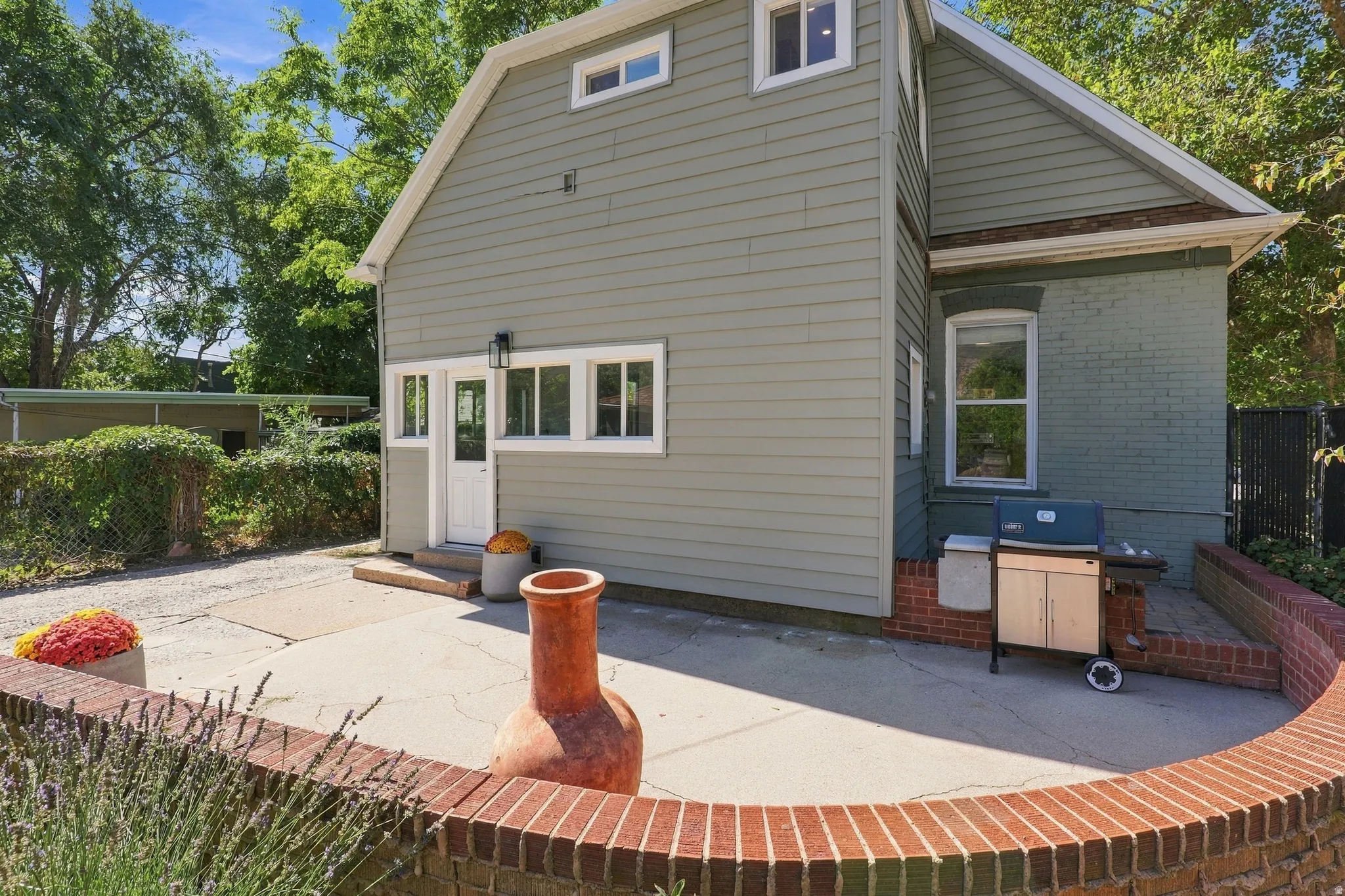 Private patio area featuring a curved brick retaining wall, concrete surfacing, and a white paneled door with transom windows