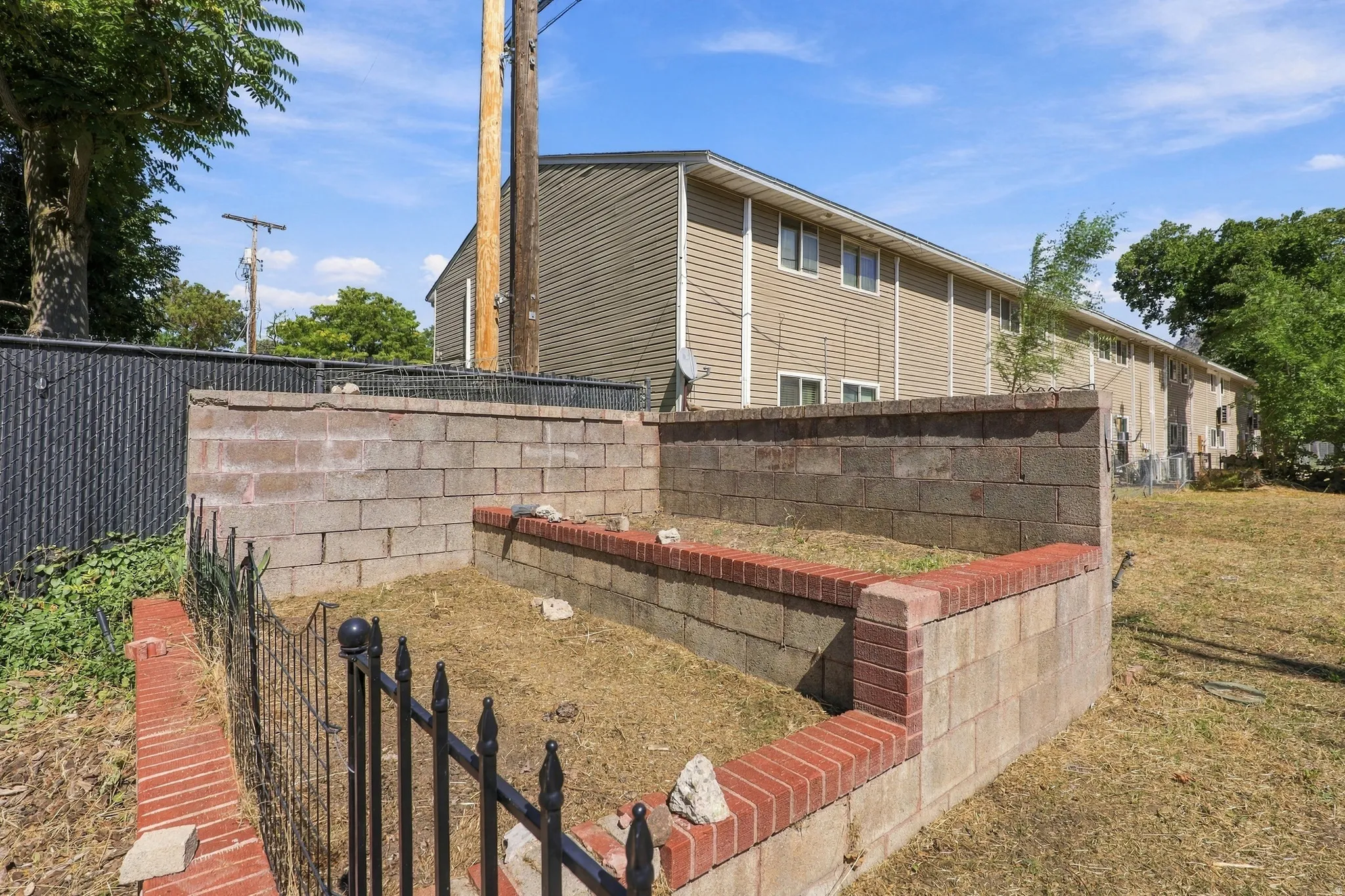 Raised garden bed with brick and concrete block construction, featuring an ornamental metal fence