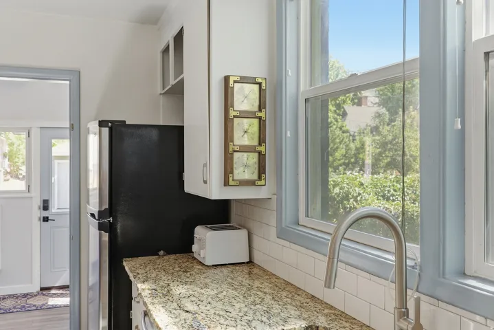 Kitchen featuring granite-style countertops, white subway tile backsplash, white cabinetry, and an undermount sink with a gooseneck faucet