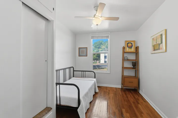 Hardwood flooring, white walls, and a ceiling fan with integrated lighting