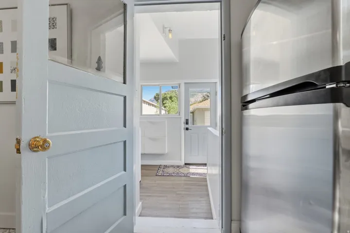Paneled interior door with a brass knob, wood-finish flooring, and a stainless steel refrigerator