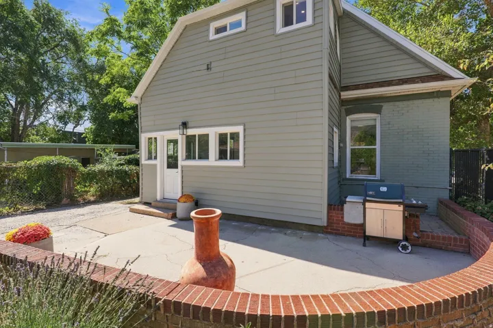 Private patio area featuring a curved brick retaining wall, concrete surfacing, and a white paneled door with transom windows