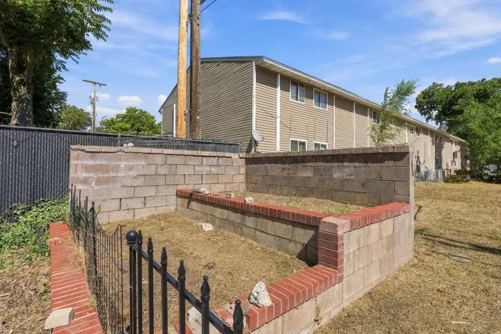 Raised garden bed with brick and concrete block construction, featuring an ornamental metal fence