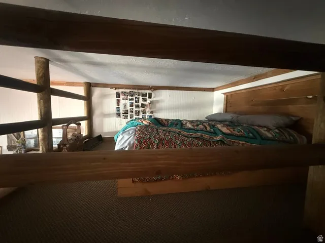 Loft area featuring wood-finish railing and built-in bed frame with headboard