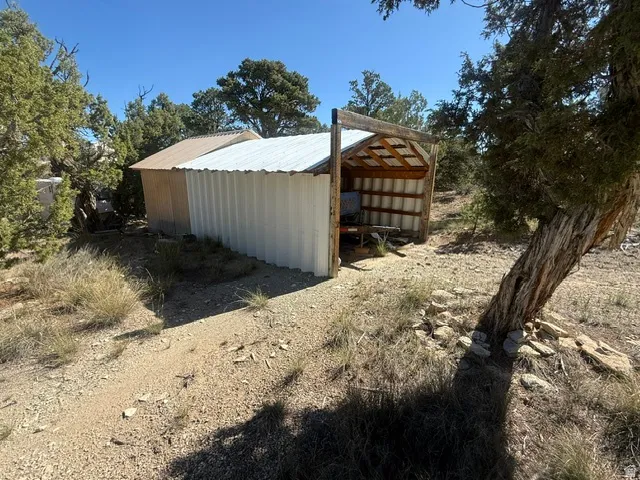 Corrugated metal structure with an open-sided shed attachment, featuring a wood-frame roof