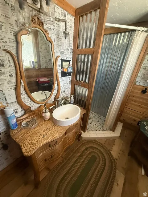 Wood-finish vanity with an oval vessel sink, ornate mirror, and industrial-style lighting