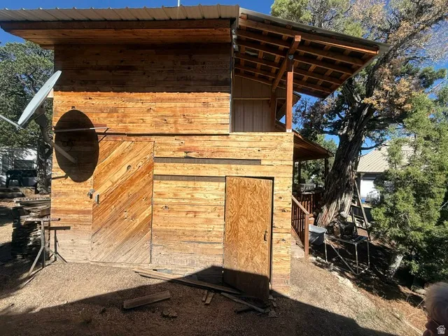 Wood-sided structure with a metal roof, featuring two distinct entry doors and an exposed beam ceiling on the upper level
