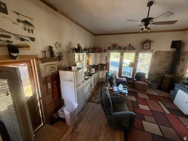 Wood-finish flooring, stone accent wall, ceiling fan with integrated lighting, multiple windows, and built-in cabinetry
