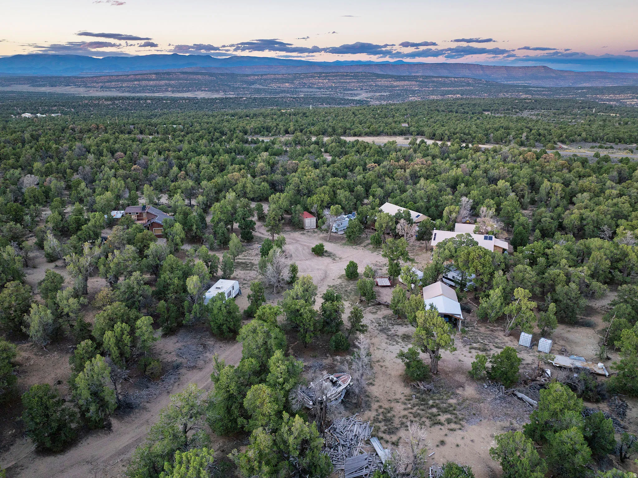 Expansive property featuring dense tree coverage, multiple structures, and a distant mountain range