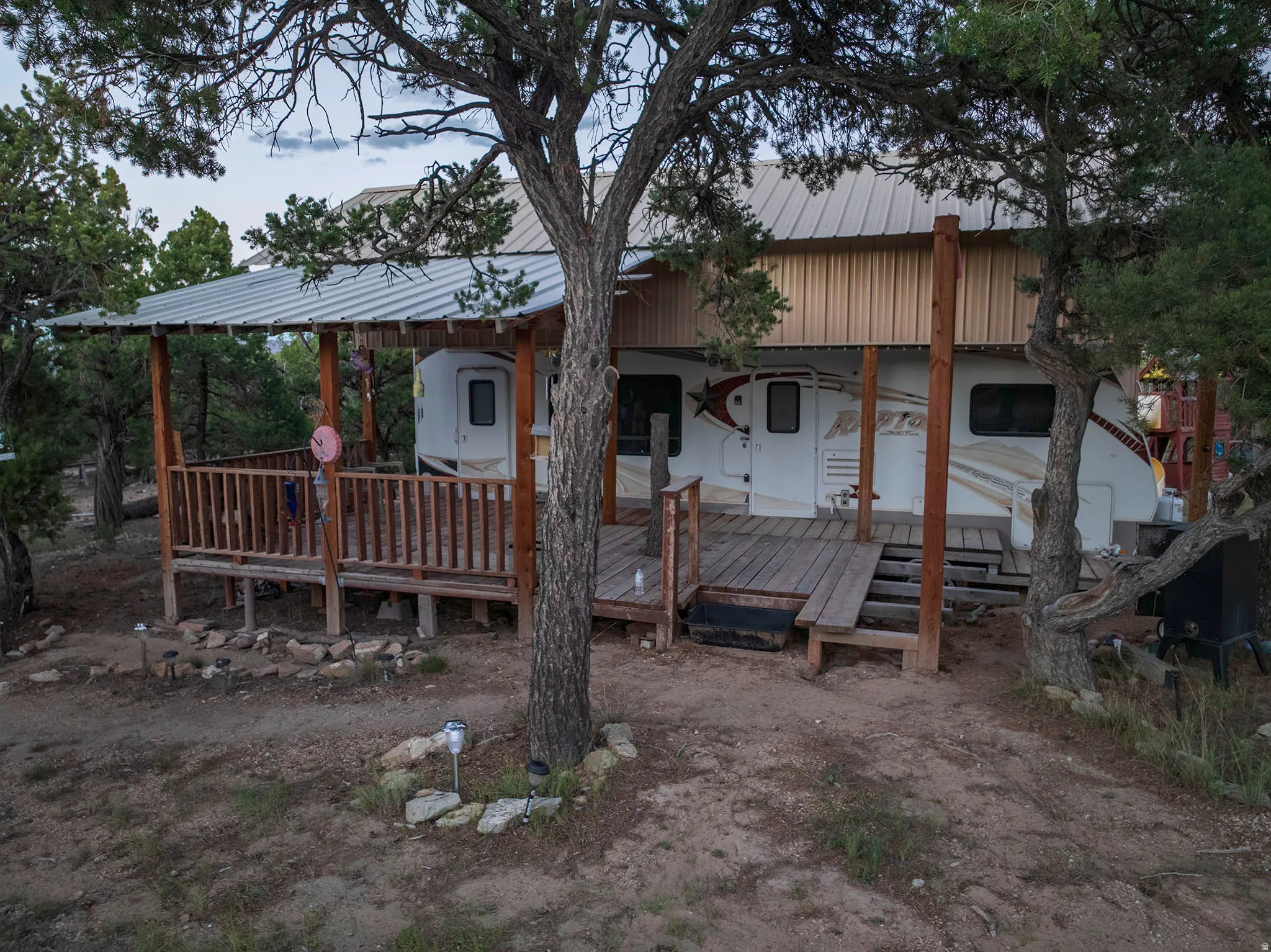 Expansive wood deck with a slatted railing, covered by a corrugated metal roof