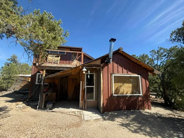 Two-story structure with a covered entry, corrugated metal siding, and an exposed wood-beam balcony