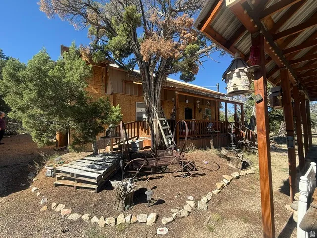 Wood-finish exterior with a covered porch featuring wooden railings and posts, and a corrugated metal roof