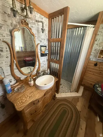 Wood-finish vanity with an oval vessel sink, an ornate wood-framed mirror, and wood-finish flooring