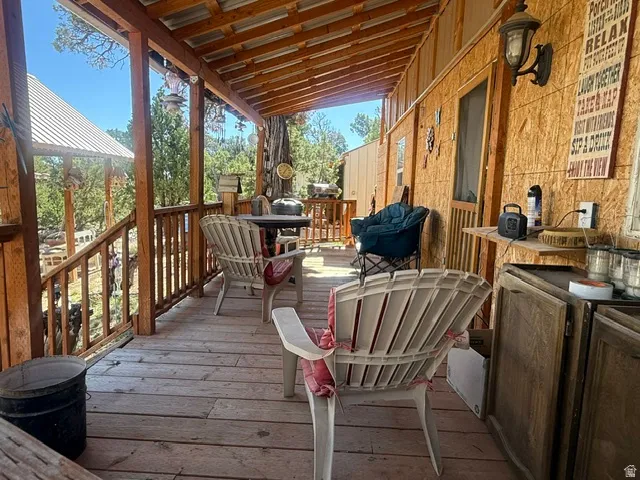 Covered porch featuring a wood deck, wood railings, and an exposed beam ceiling