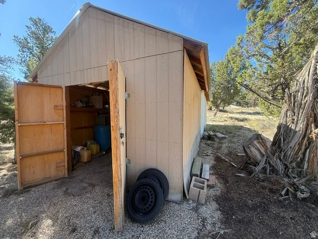 Exterior storage shed with double doors, wood-finish siding, and a gabled roof