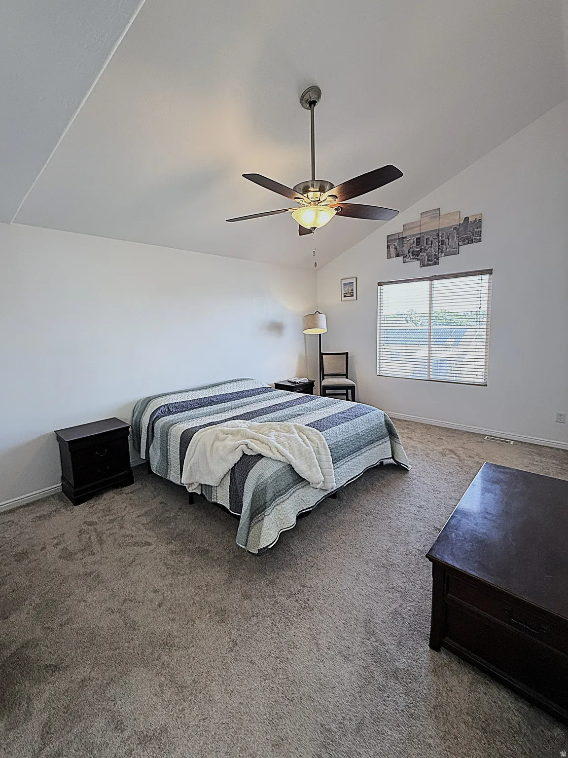 Vaulted ceiling, ceiling fan with integrated lighting, carpeted flooring, window with blinds, and built-in window frame