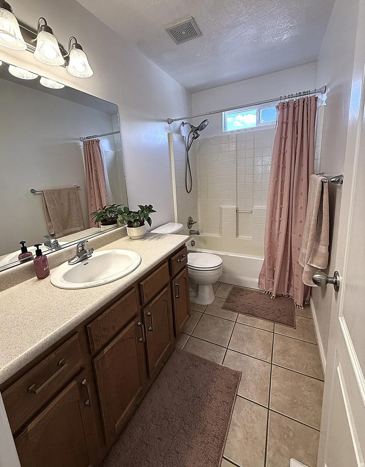 Single vanity with an integrated sink, built-in cabinetry, and a shower-tub combination with white tile surround